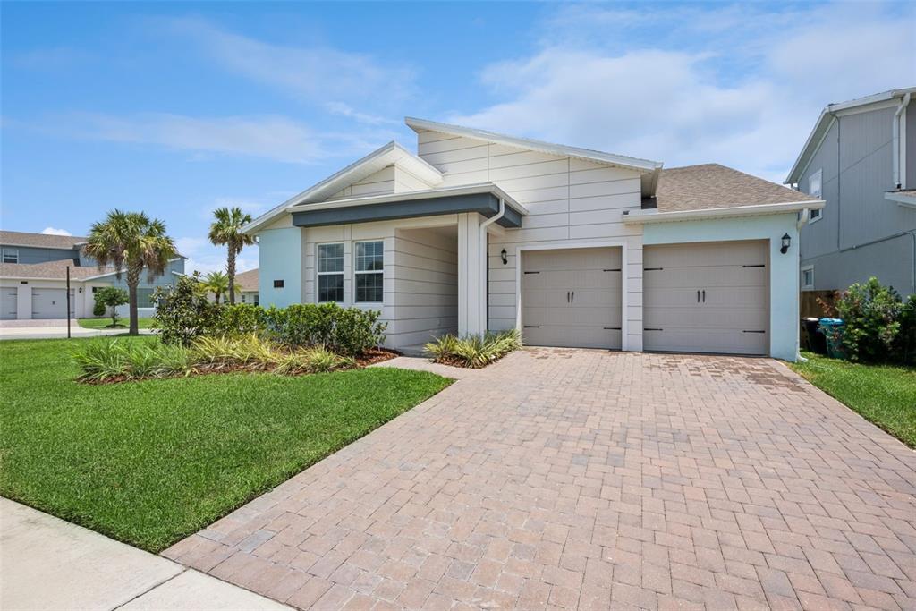 A single-story house with a two-car garage and a paved driveway under a blue sky — 19307 BANFIELD PLACE, ORLANDO, FL