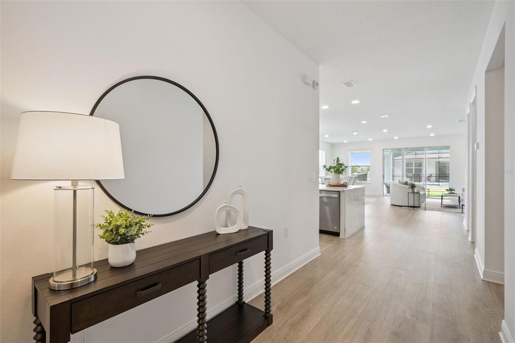 A bright entryway features a dark wood console table, a round mirror, and light flooring — 19307 BANFIELD PLACE, ORLANDO, FL