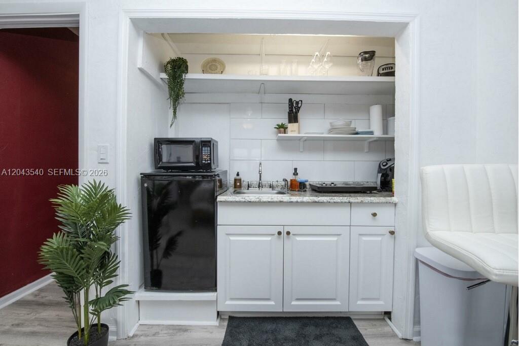 A small kitchen nook features white cabinets, a granite countertop, and a built-in microwave — 2721 SW 30th Ave, Miami FL 33133, MIAMI, FL