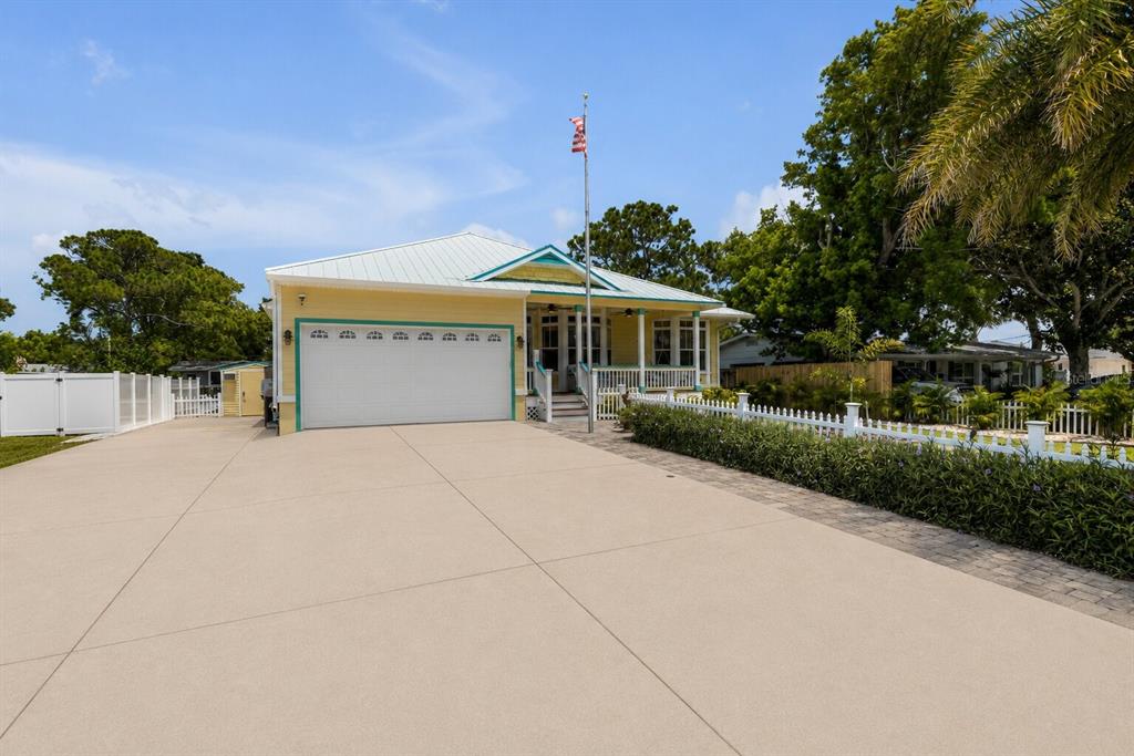 A yellow house with a white metal roof and a large concrete driveway — 521 S PENINSULA AVENUE, NEW SMYRNA BEACH, FL