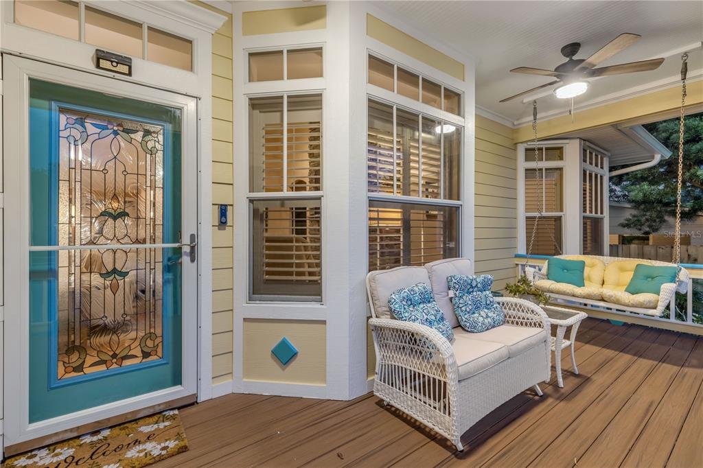 A covered front porch features a stained-glass door, wicker furniture, and a hanging porch swing — 521 S PENINSULA AVENUE, NEW SMYRNA BEACH, FL