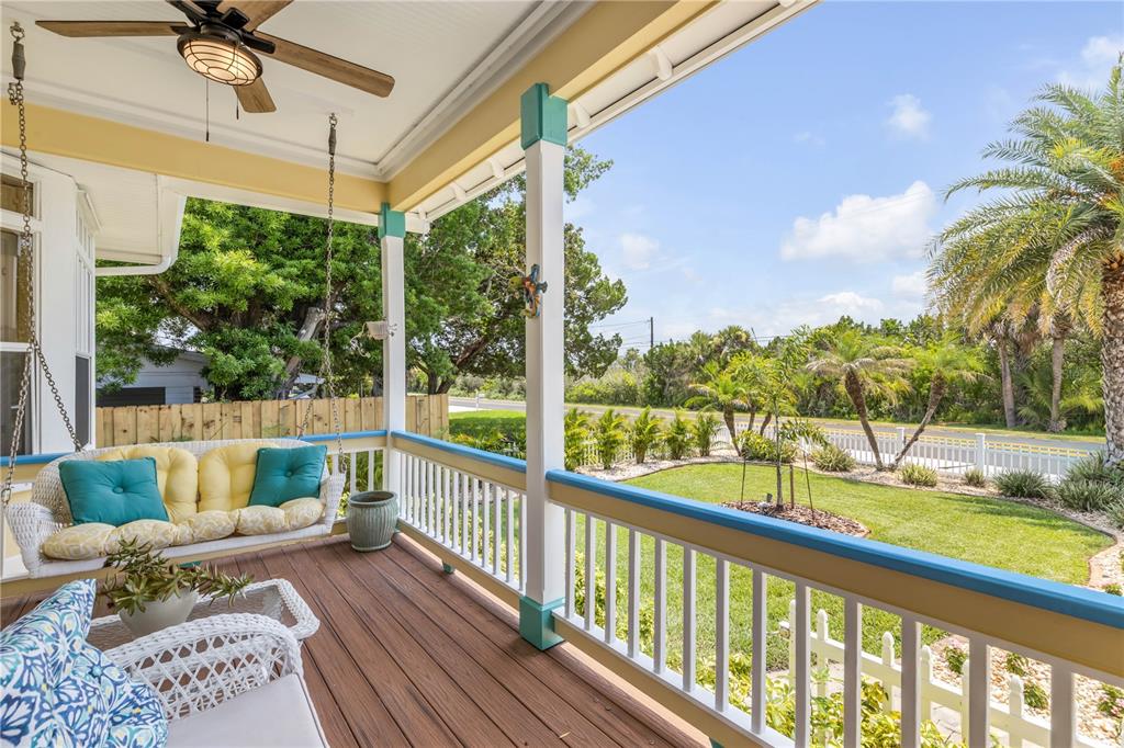 A covered porch features a hanging swing, ceiling fan, and views of a grassy yard — 521 S PENINSULA AVENUE, NEW SMYRNA BEACH, FL