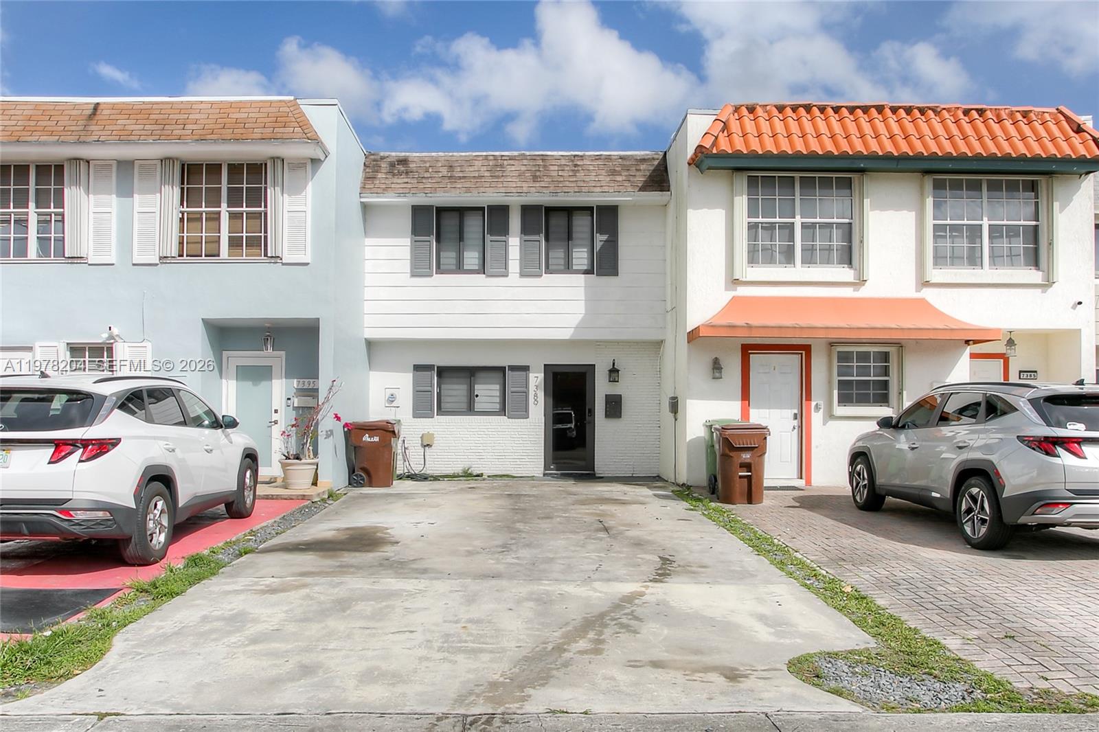 Three attached townhouses feature concrete driveways, parked cars, and varied exterior architectural styles — 7389 W 18th Ave, Hialeah FL 33014, HIALEAH, FL
