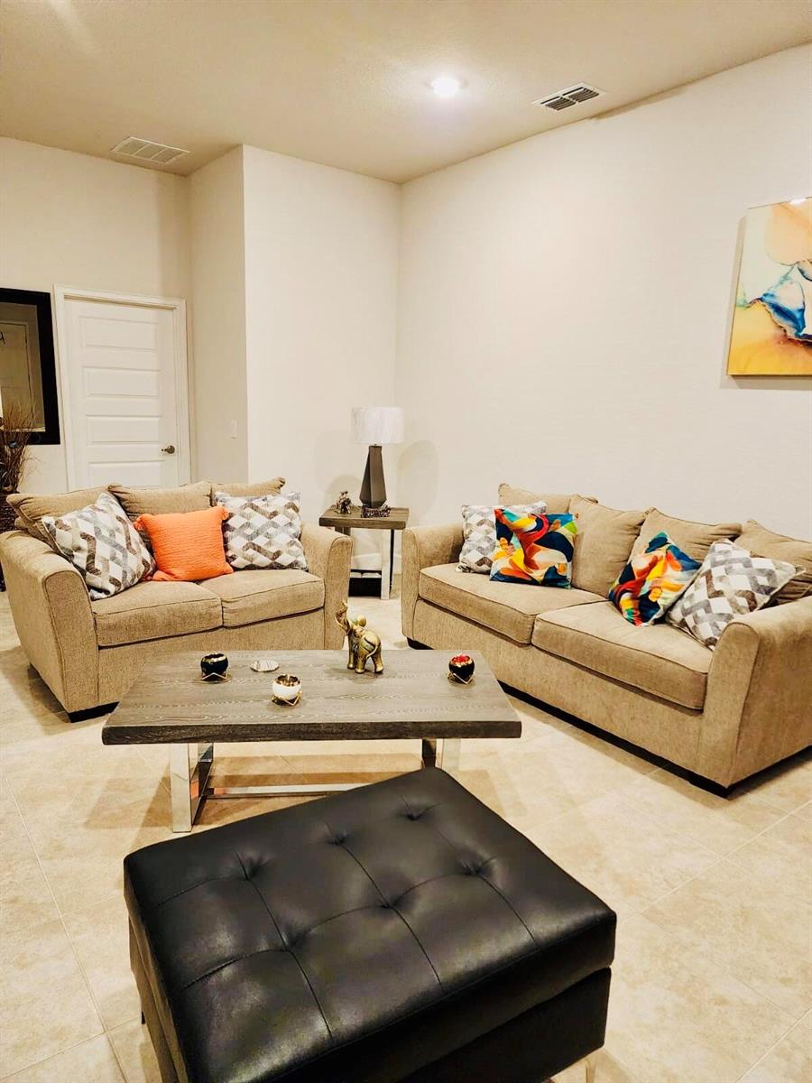 A living room features two beige sofas, a wooden coffee table, and a black ottoman — 640 Tanaro Lane, FL 33844, FL