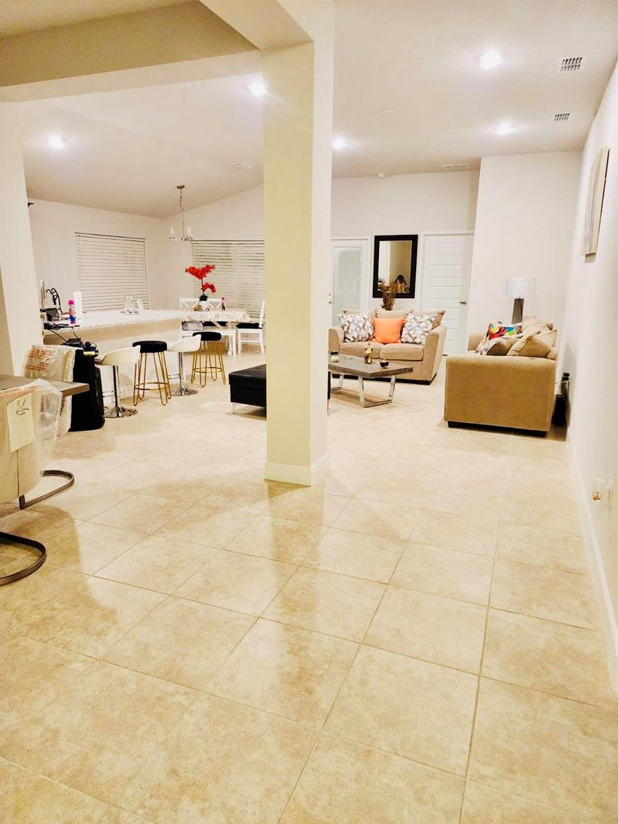 An open-concept living room and kitchen area with light tile flooring and neutral furniture — 640 Tanaro Lane, FL 33844, FL