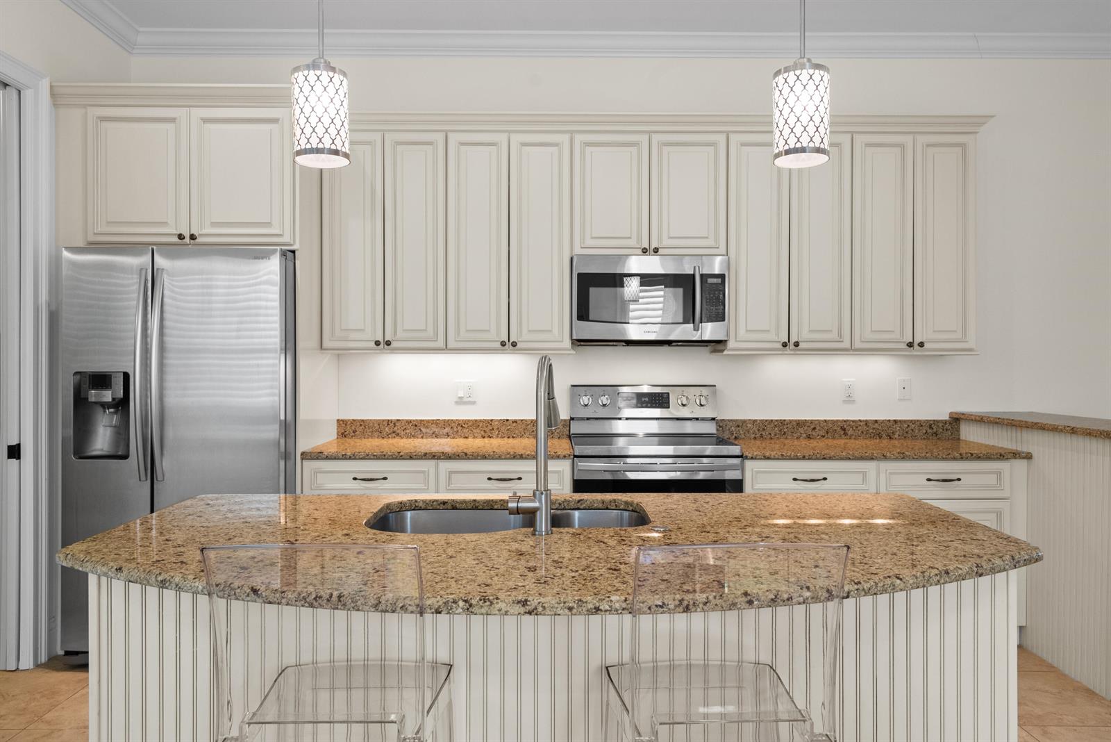 A kitchen features off-white cabinets, granite countertops, stainless steel appliances, and a central island — 10187 S Ocean Drive # 1, Jensen Beach FL 34957, JENSEN BEACH, FL