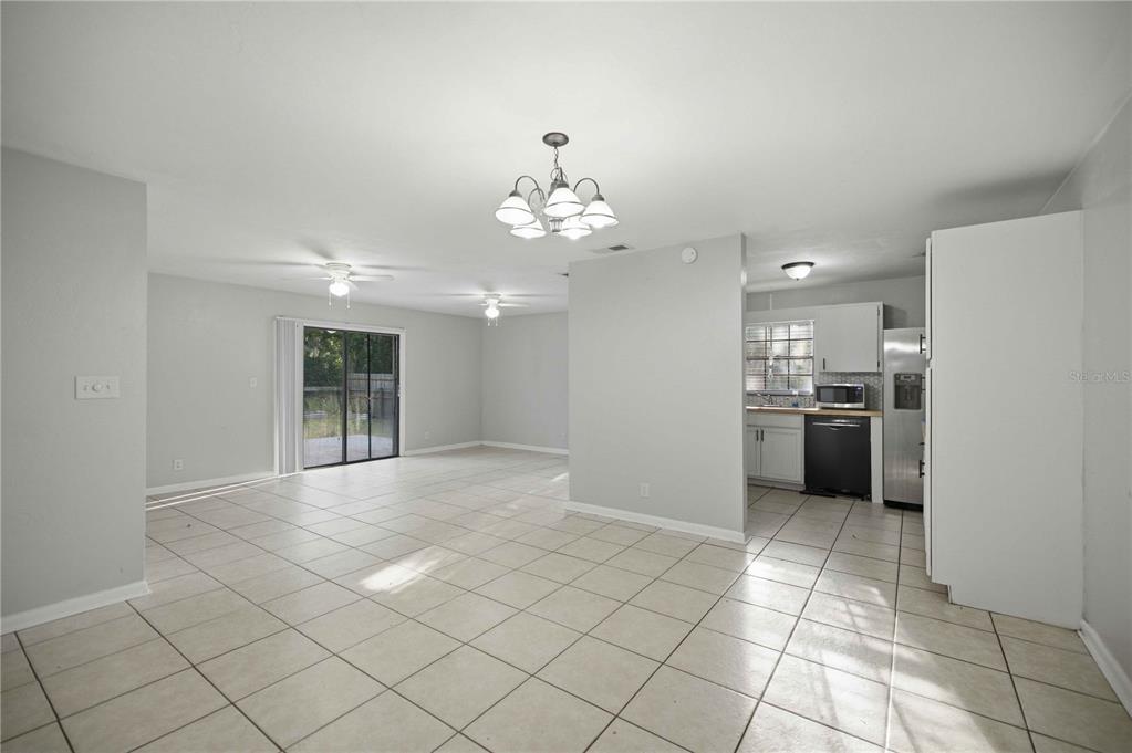 An open-concept living and dining area features light gray walls and beige tile flooring — 2351 NE 40TH STREET, OCALA, FL