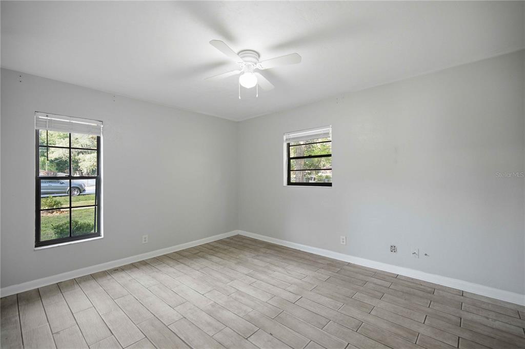 An empty bedroom features light gray walls, wood-look tile flooring, and a ceiling fan — 2351 NE 40TH STREET, OCALA, FL