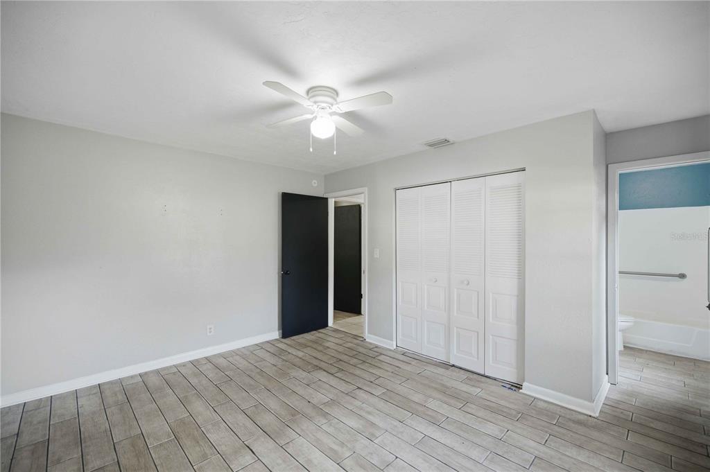 A bedroom features light gray walls, wood-look tile flooring, a ceiling fan, and a closet — 2351 NE 40TH STREET, OCALA, FL