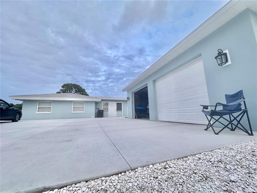 A light blue house exterior features a concrete driveway, a garage, and a folding chair — 2746 53RD STREET, SARASOTA, FL