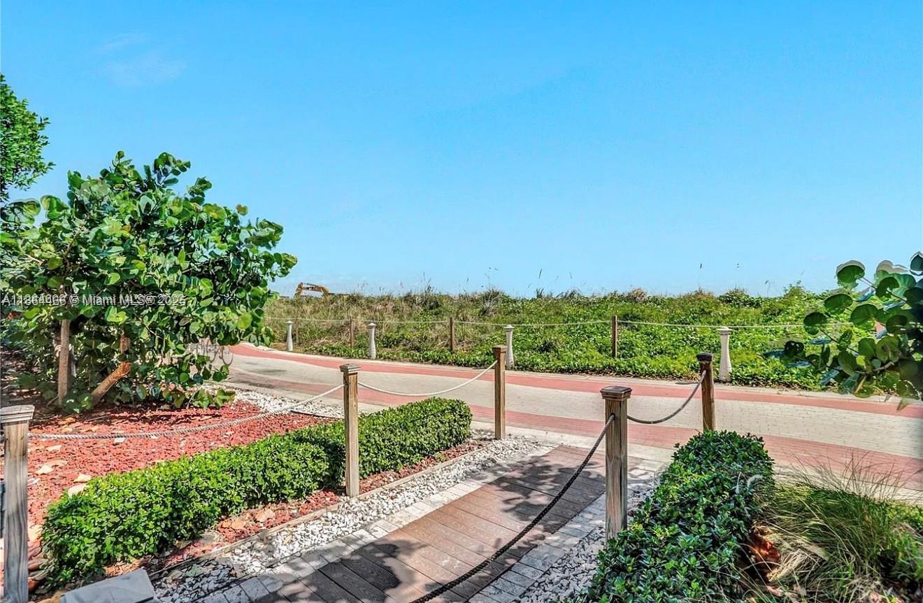 A wooden walkway leads to a paved path bordered by rope fencing and lush greenery — 6423 E Collins Ave # 206, Miami Beach FL 33141, MIAMI BEACH, FL