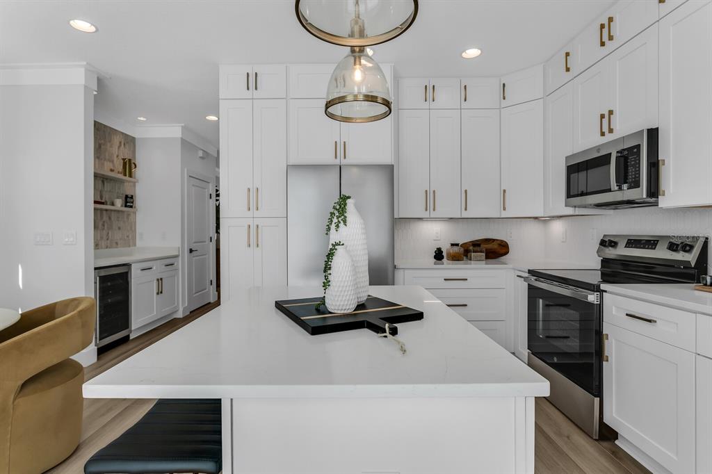 A modern kitchen features white cabinetry, a large quartz island, and stainless steel appliances — 2138 W CHESTNUT STREET, TAMPA, FL