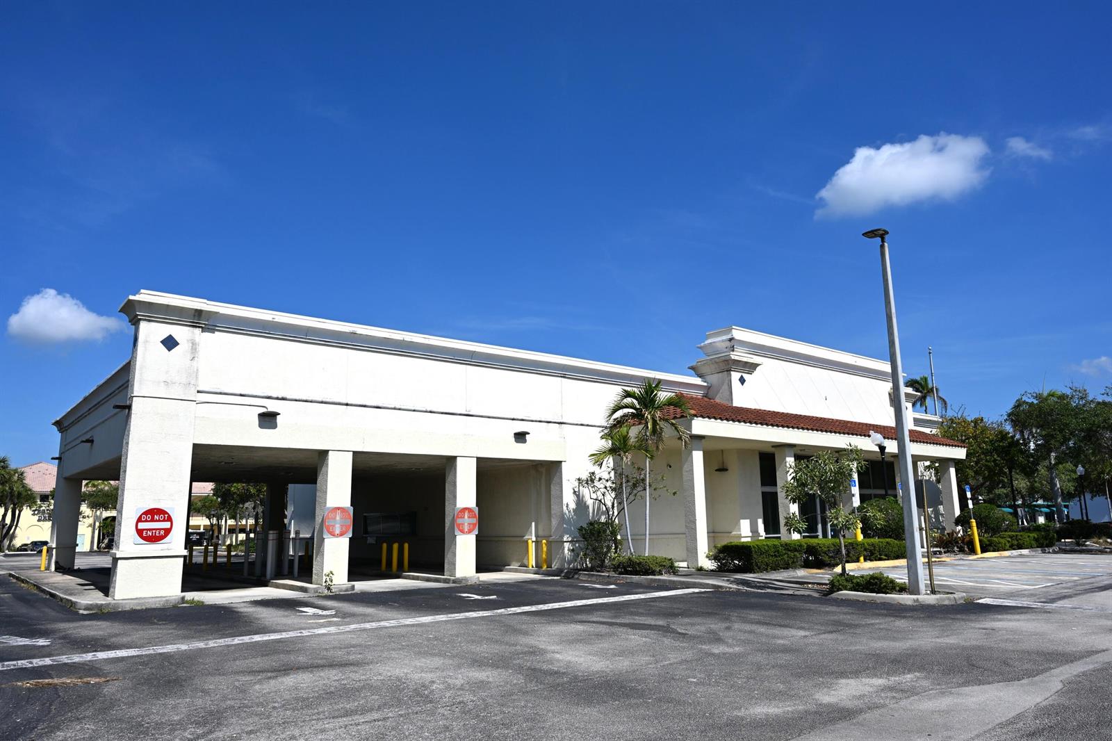 A vacant commercial building with a drive-thru lane under a covered overhang against blue skies — 150 Tequesta Drive, Tequesta FL 33469, TEQUESTA, FL