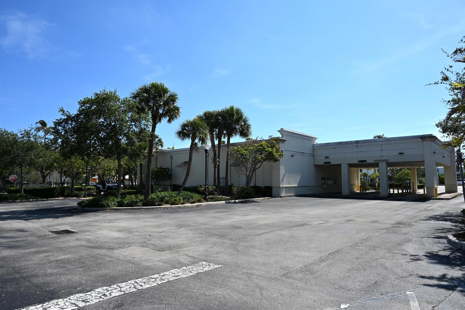 A commercial building with a drive-thru canopy stands next to a parking lot and palms — 150 Tequesta Drive, Tequesta FL 33469, TEQUESTA, FL
