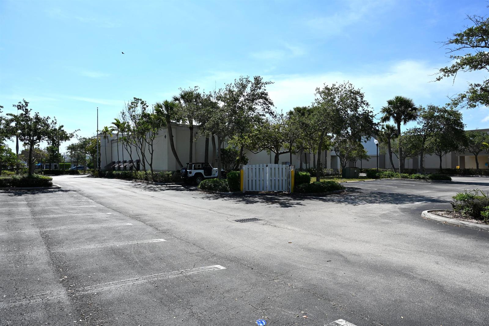 A paved parking lot sits in front of a commercial building with trees and fencing — 150 Tequesta Drive, Tequesta FL 33469, TEQUESTA, FL