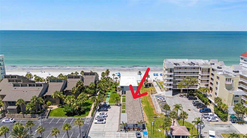 An aerial view shows a long, narrow building with a shingled roof near the beach — 16850 GULF BOULEVARD UNIT 4, NORTH REDINGTON BEACH, FL