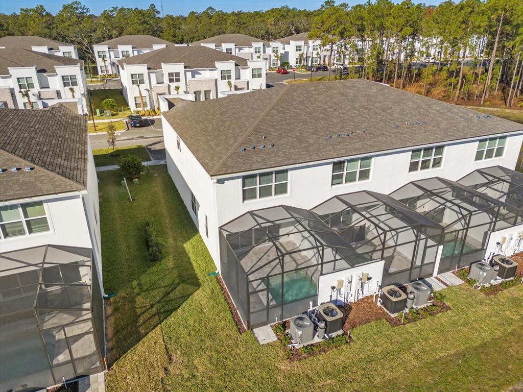 An aerial view shows the back of several townhomes with screened-in pools and HVAC units — 1398 PEACEFUL NATURE WAY, CLERMONT, FL
