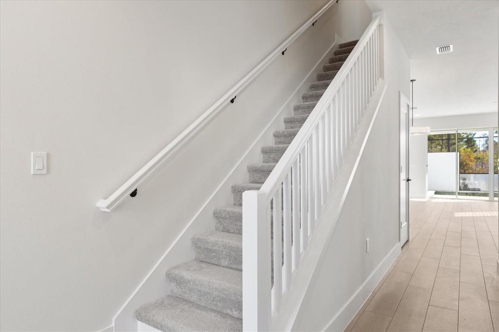 A carpeted staircase with a white railing and handrail leads to an upper floor — 1398 PEACEFUL NATURE WAY, CLERMONT, FL