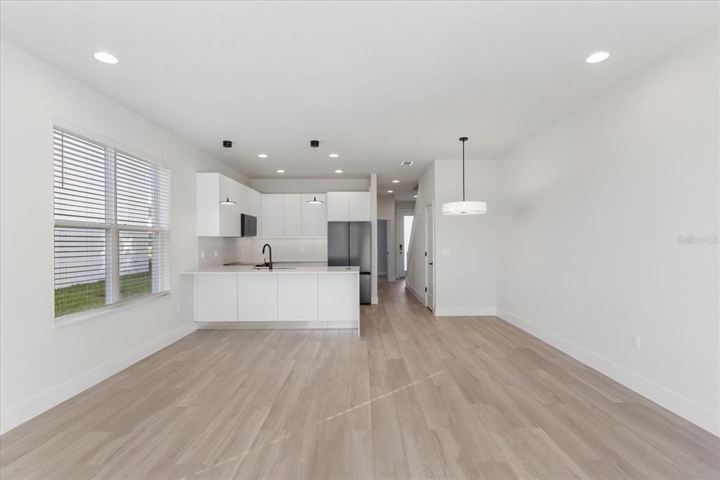 A modern kitchen with white cabinets and a peninsula overlooks an open-concept living area — 1398 PEACEFUL NATURE WAY, CLERMONT, FL