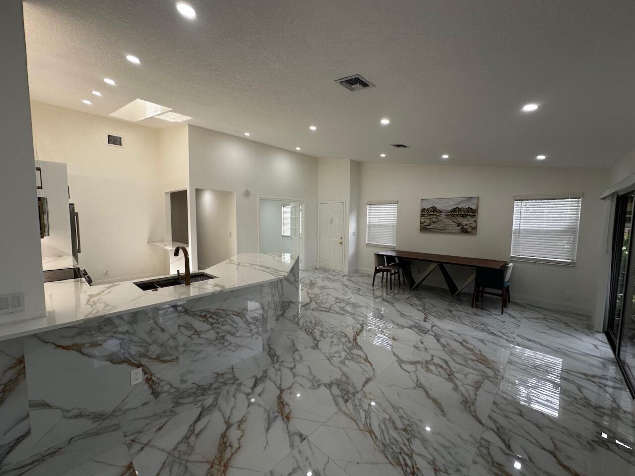A modern kitchen and dining area with white marble flooring and matching marble countertops — 2173 Discovery Circle W, Deerfield Beach FL 33442, DEERFIELD BEACH, FL