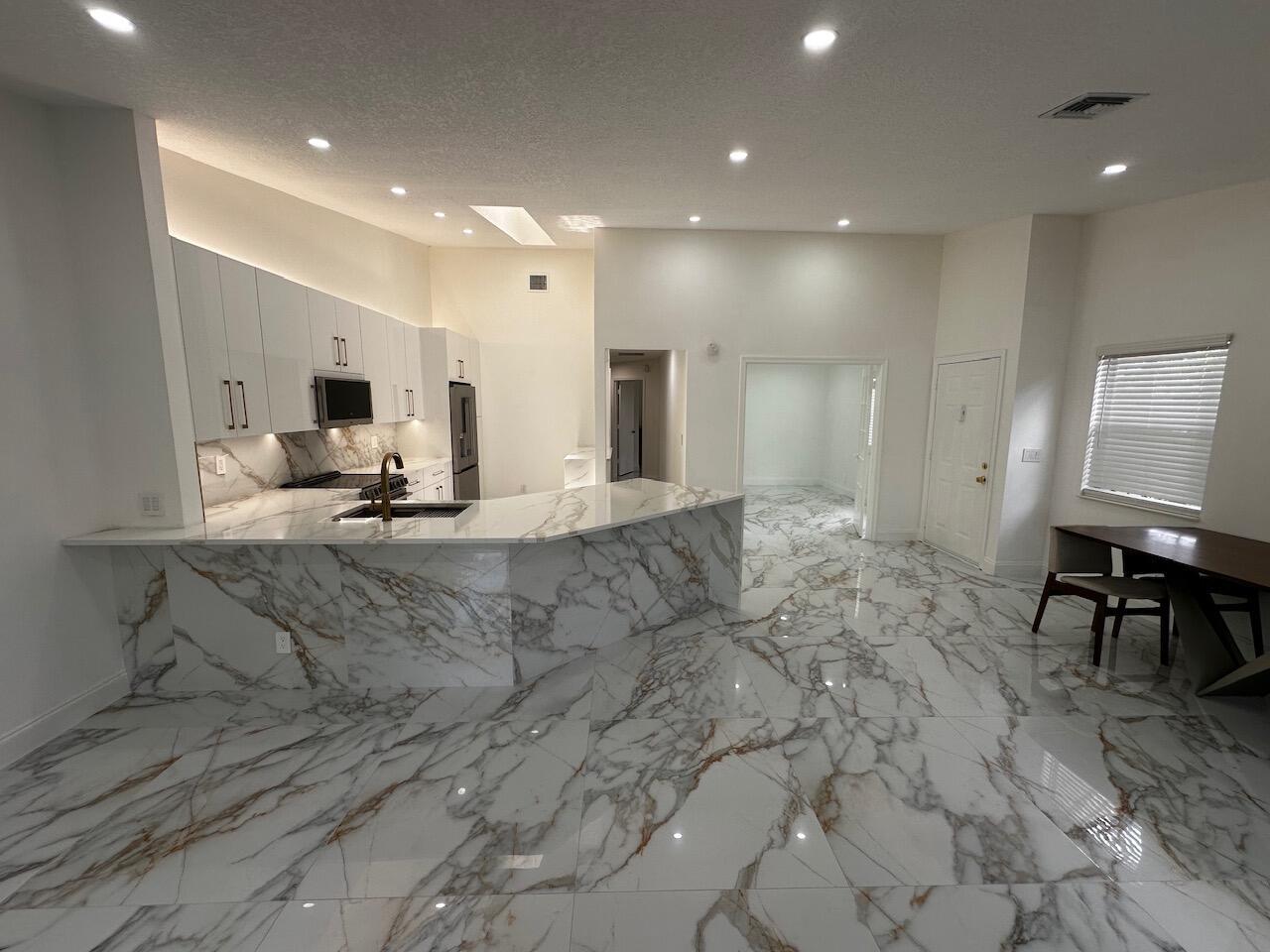 A modern kitchen with white cabinets, marble-patterned countertops, and matching marble-look tile flooring — 2173 Discovery Circle W, Deerfield Beach FL 33442, DEERFIELD BEACH, FL