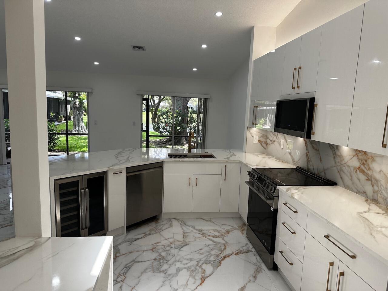 A modern kitchen features white marble countertops, matching flooring, and stainless steel appliances — 2173 Discovery Circle W, Deerfield Beach FL 33442, DEERFIELD BEACH, FL