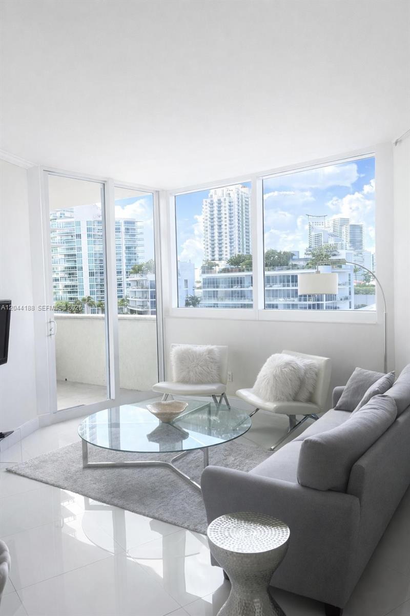 A bright living room features a glass coffee table, white chairs, and a gray sofa — 300 S Pointe Dr # 706, Miami Beach FL 33139, MIAMI BEACH, FL