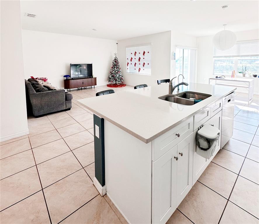 A kitchen island with a double sink sits in front of an open-concept living area — 1122 BRIMSTONE CIR, WINTER HAVEN, FL