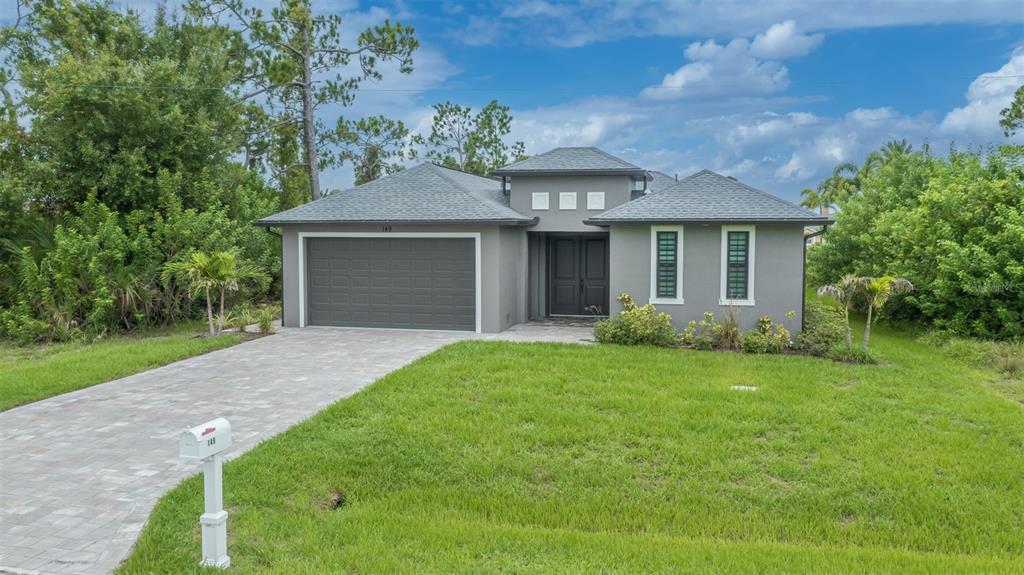 A gray single-story house with a paved driveway, a two-car garage, and a front lawn — 149 WAHOO DRIVE, ROTONDA WEST, FL