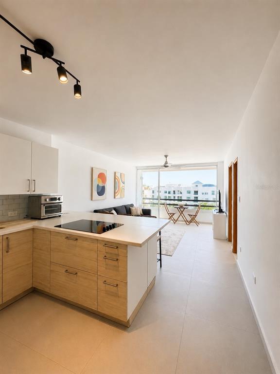 A modern kitchen with light wood cabinets and a breakfast bar opens to a living area — 0 C. HORIZONTE, CAROLINA, PR