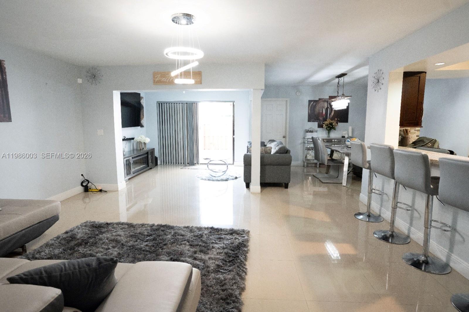 An open-concept living and dining area features tile flooring, modern lighting, and a breakfast bar — 333 Ives Dairy Rd # A33306, Miami FL 33179, MIAMI, FL