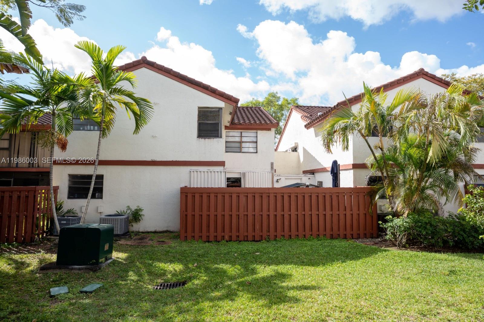 The exterior view shows two white townhouses with brown tile roofs and a wooden fence — 333 Ives Dairy Rd # A33306, Miami FL 33179, MIAMI, FL