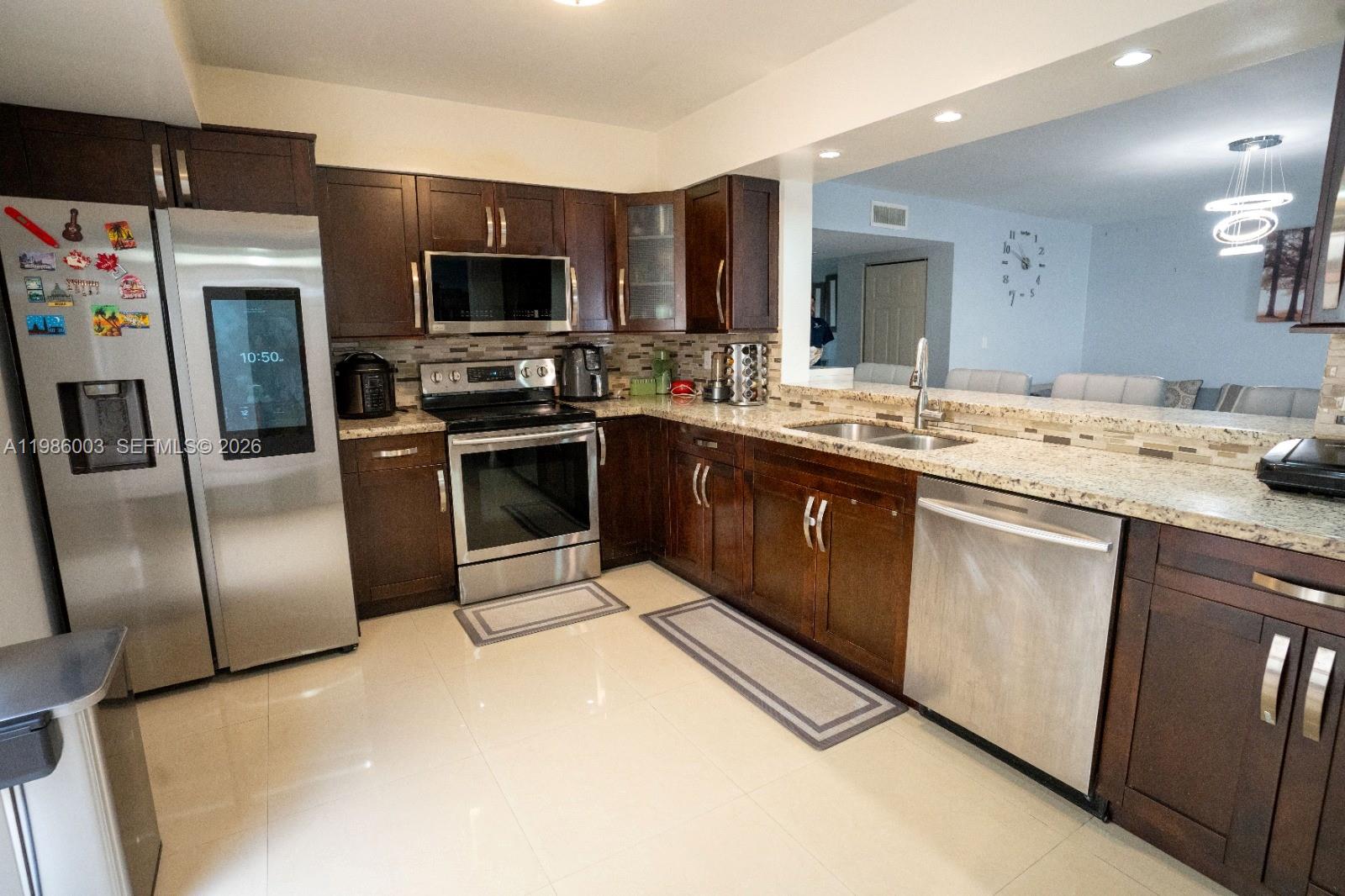 A kitchen features dark wood cabinets, stainless steel appliances, and granite countertops — 333 Ives Dairy Rd # A33306, Miami FL 33179, MIAMI, FL