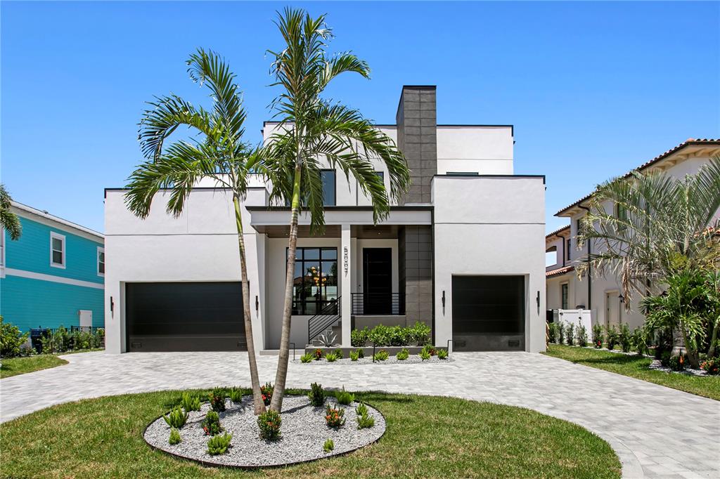 A modern two-story house with a paved driveway, two garages, and a palm tree at night — 5007 W SAN MIGUEL STREET, TAMPA, FL