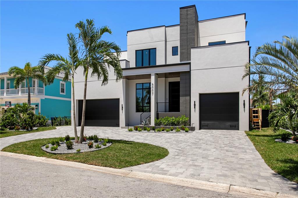 A modern two-story house with a white stucco facade, dark garage doors, and a palm tree — 5007 W SAN MIGUEL STREET, TAMPA, FL