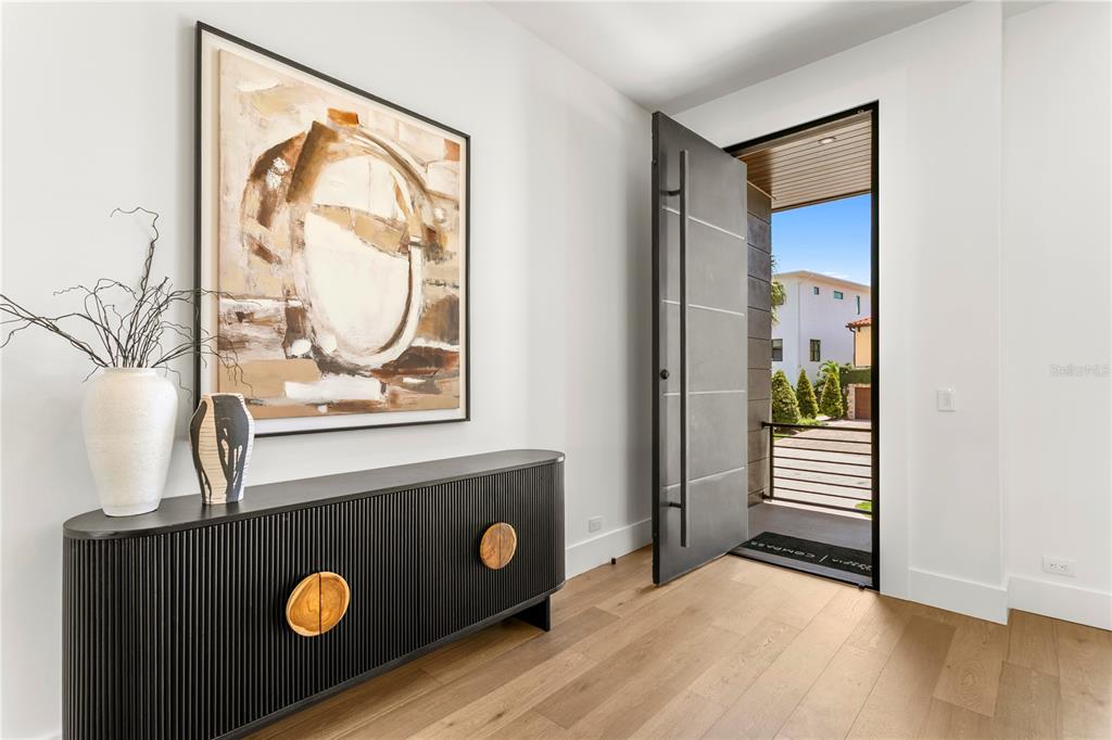 The exterior of a modern home features a raised entryway, dark door, and landscaped garden — 5007 W SAN MIGUEL STREET, TAMPA, FL