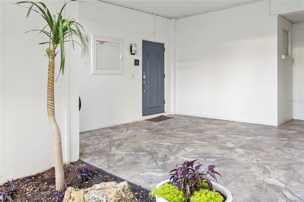 A gray front door with the number 11 sits on a tiled patio area — 400 GOLDEN GATE POINT UNIT 11, SARASOTA, FL