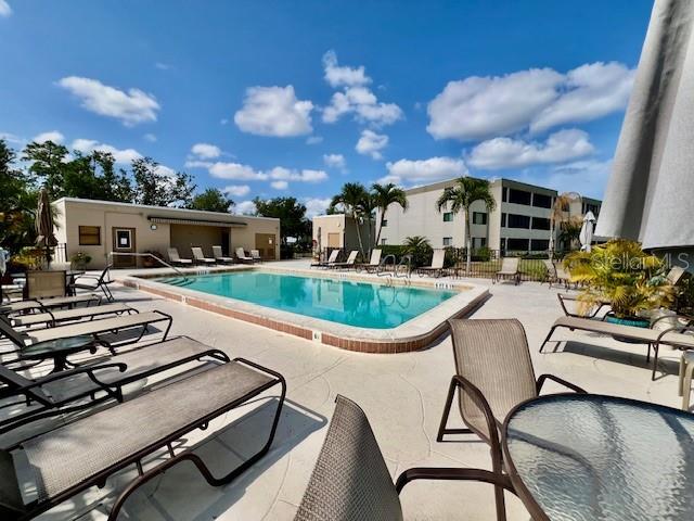 A swimming pool is surrounded by lounge chairs and a patio area near a building — 801 ISLAMORADA BOULEVARD UNIT 23B, PUNTA GORDA, FL