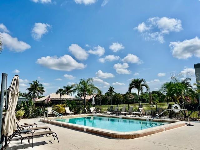 A swimming pool with lounge chairs and palm trees under a blue sky — 801 ISLAMORADA BOULEVARD UNIT 23B, PUNTA GORDA, FL