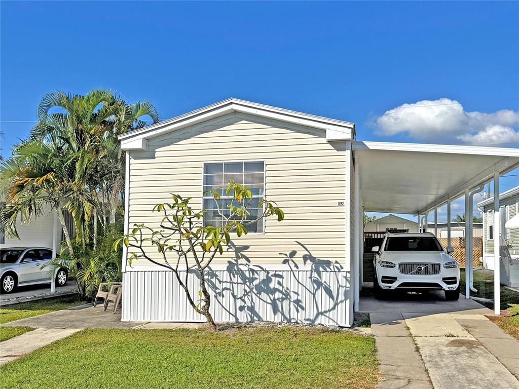 A light-colored mobile home features a carport with a white SUV parked underneath — 10101 BURNT STORE ROAD UNIT 118, PUNTA GORDA, FL