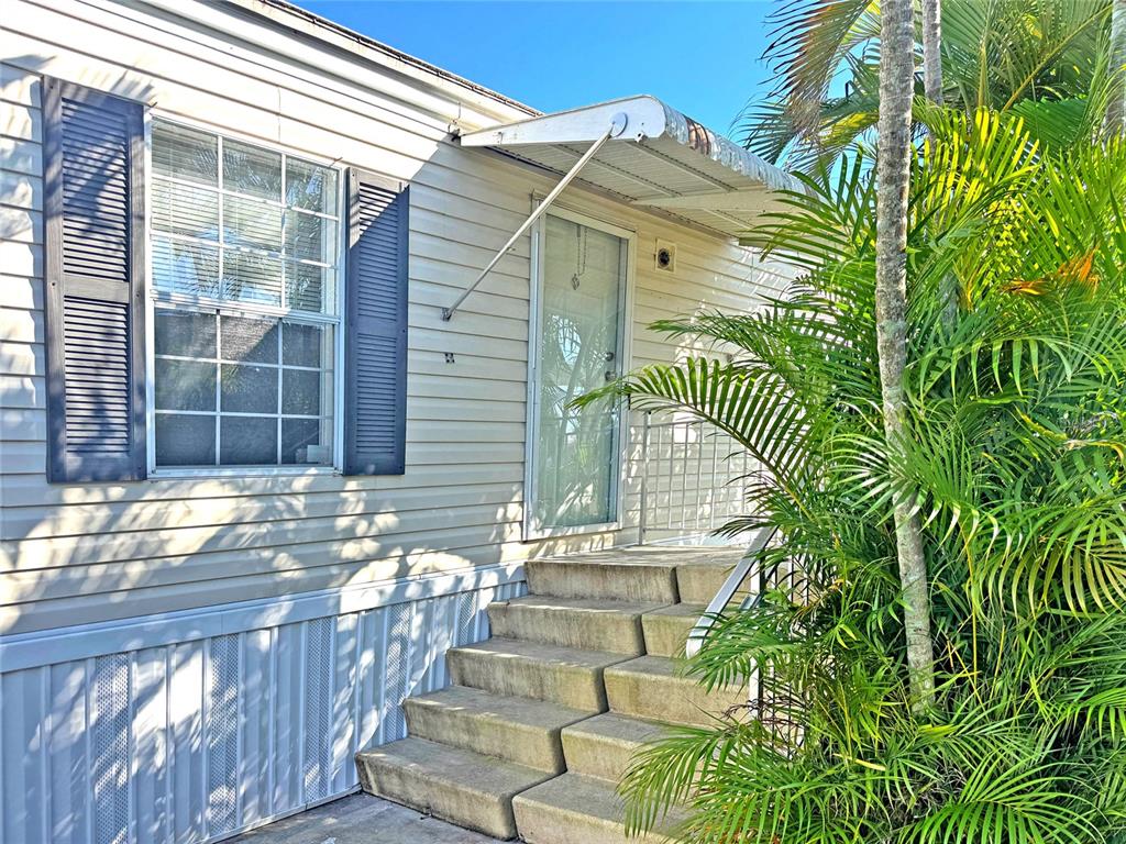 The exterior of a mobile home features light siding, a window with shutters, and concrete steps — 10101 BURNT STORE ROAD UNIT 118, PUNTA GORDA, FL