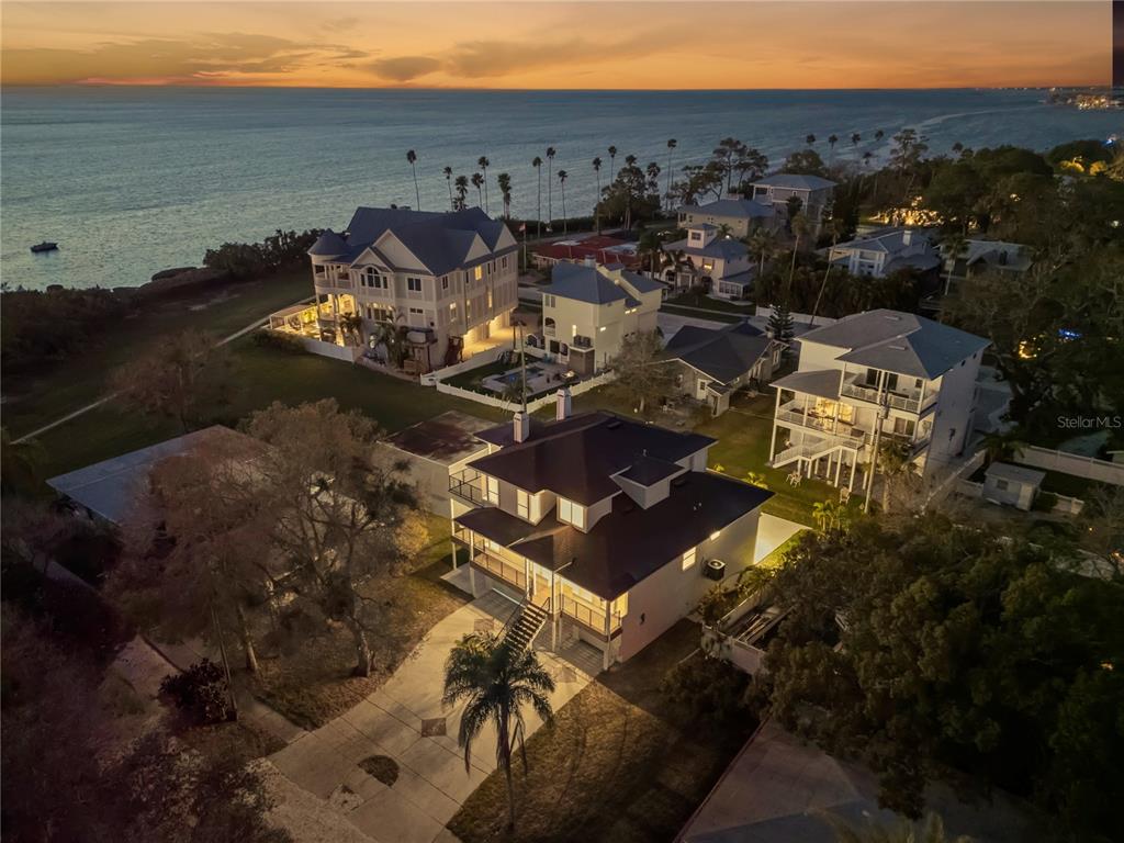 An aerial view shows several multi-story coastal homes near the ocean at sunset — 606 INDIANA AVENUE, CRYSTAL BEACH, FL
