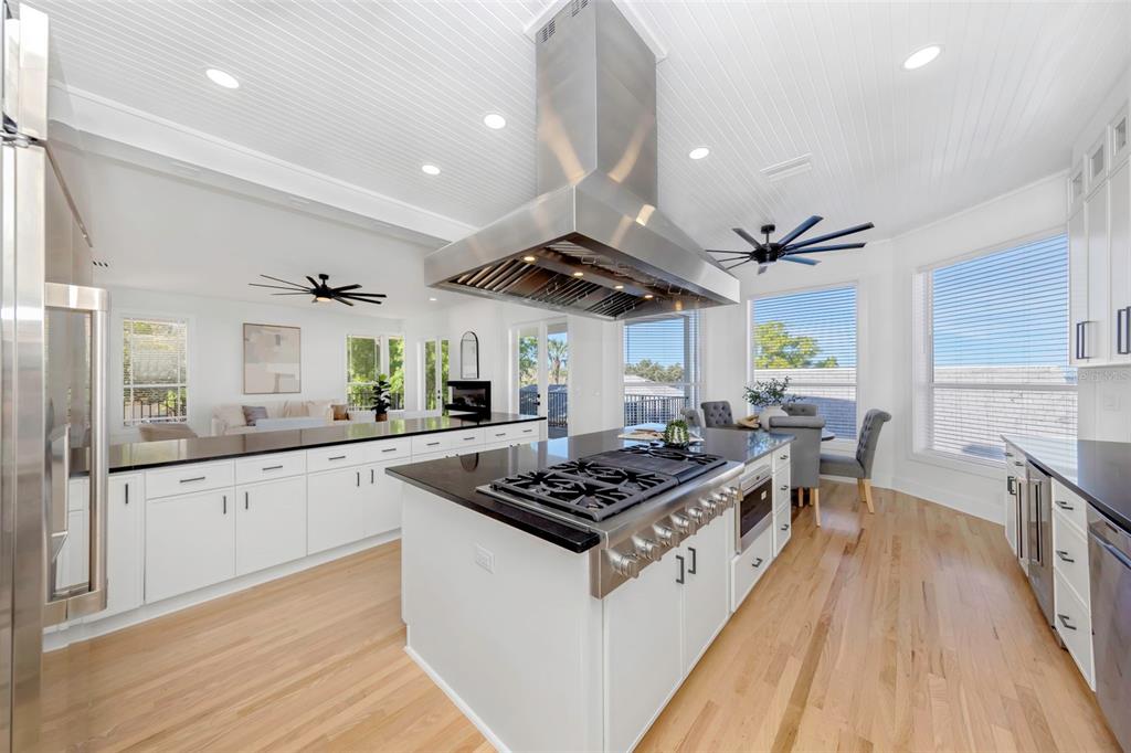 A bright bedroom features a king bed, a ceiling fan, and large windows overlooking water — 606 INDIANA AVENUE, CRYSTAL BEACH, FL