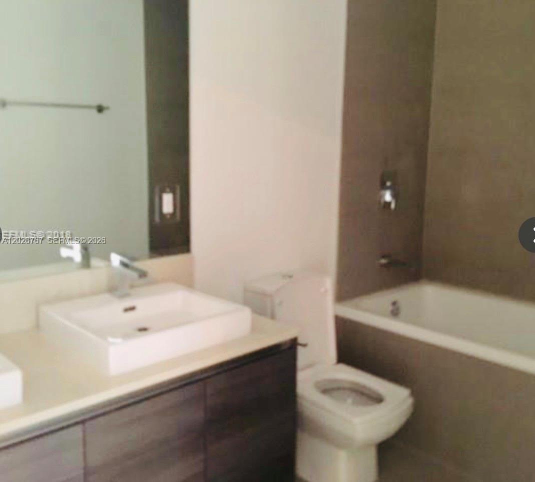 A bathroom features a white vessel sink, a dark wood vanity, and a tiled bathtub — 1080 Brickell Ave # 1703, Miami FL 33131, MIAMI, FL