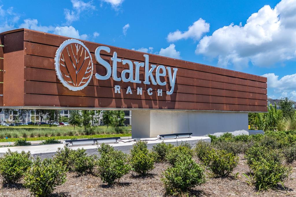 A large, modern Starkey Ranch community entrance sign stands above landscaped bushes under a blue sky — 3794 NIGHT STAR TRAIL, ODESSA, FL