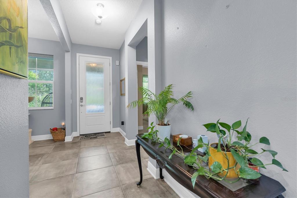 An entryway features gray walls, large tile flooring, a white front door, and a console table — 3794 NIGHT STAR TRAIL, ODESSA, FL
