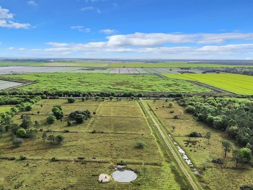 An aerial view shows a grassy field with a small pond and surrounding agricultural land — 2777 Everhigh Acres Road Road, Clewiston FL 33440, CLEWISTON, FL