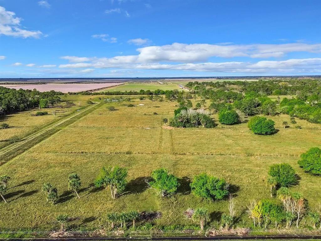 An aerial view of a large, grassy field with scattered trees and a distant horizon — 2777 Everhigh Acres Road Road, Clewiston FL 33440, CLEWISTON, FL
