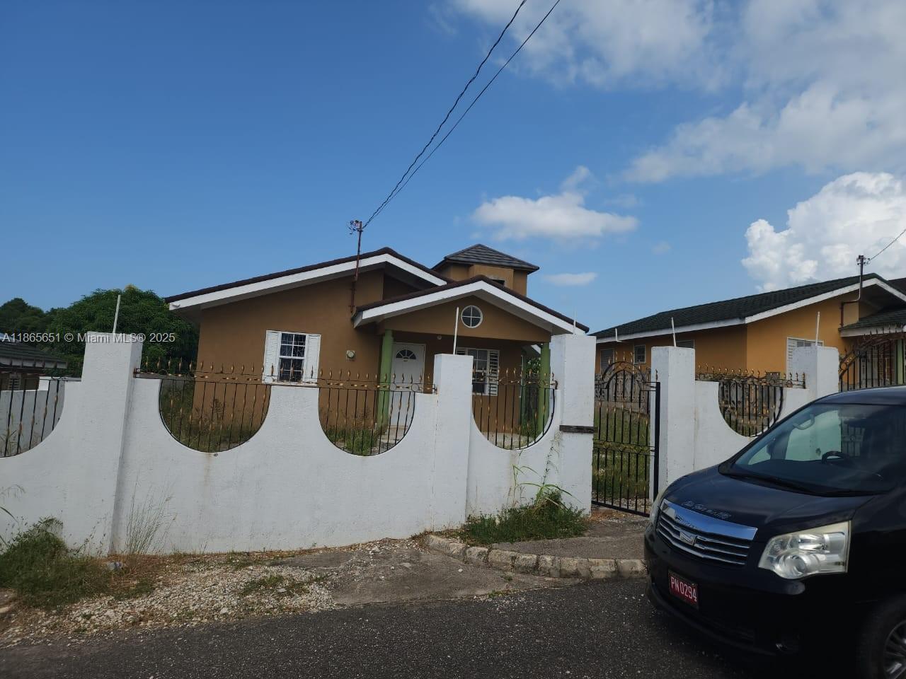A tan house with a white fence and a black car parked in the foreground — 00 Stonebrook Vista, Trelawny, NA, NA