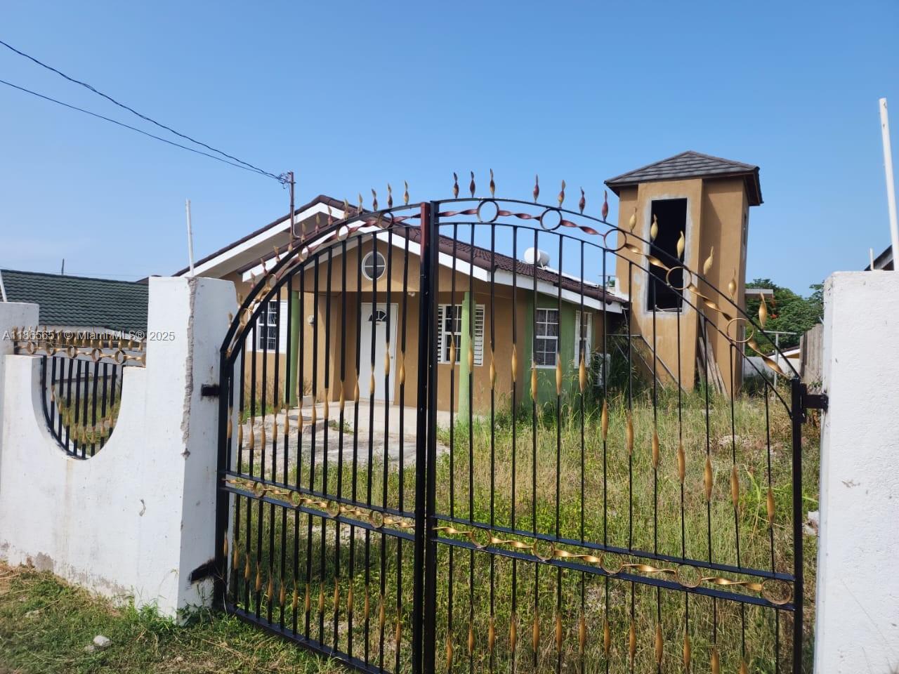 A single-story house with a tower structure behind a decorative black metal gate — 00 Stonebrook Vista, Trelawny, NA, NA